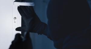 A man looks to pick the lock of a front door