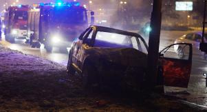 A car crashed into a post with fire engines in the background