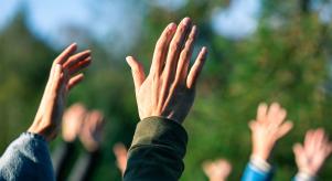 A group of people standing outside with their hands in the air