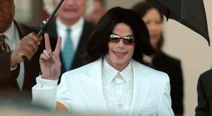 Michael Jackson flashes the 'Peace' sign to crowds of supporters as he arrives at court