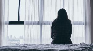 A woman sitting on a bed looking out of the window