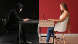 A hacker on his laptop sits opposite a woman on her laptop