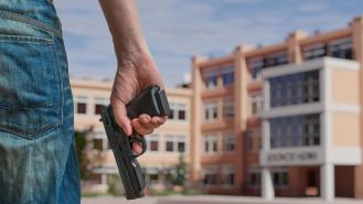 A man holding a gun outside of a high school