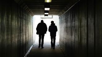 two people walk to the light at the end of a tunnel