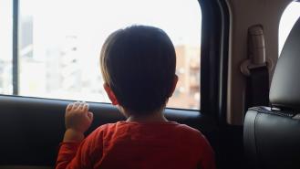 Little boy sitting in the car and look out from the car window.