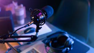 A podcast microphone with headphones on the desk