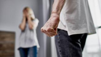A man clenches his fist while a woman holds her head in despair