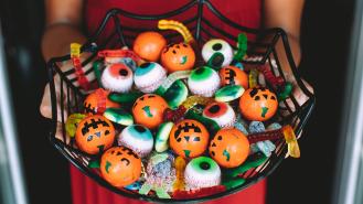 A woman holding a bowl of Halloween sweets