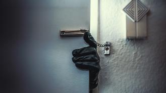 A leather-gloved hand reaching around a door