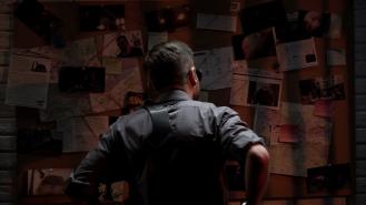 A detective looking at an evidence board