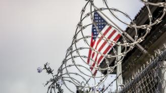 Barbed wire in front of a US flag at a prison