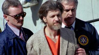 Ted Kaczynski is flanked by federal agents as he is led to a car from a federal courthouse