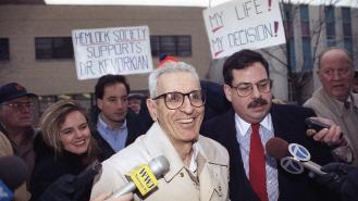 Dr Jack Kevorkian smiles as he arrives at police headquarters in 1993 surrounded by media and his supporters