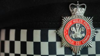 South Wales Police badge on a black and white checked background