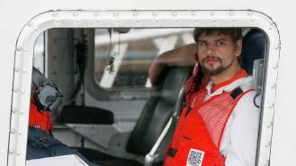 Nathan Carman looks out the window of a small boat after being rescued at sea