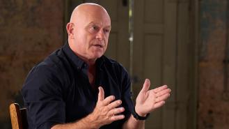Ross Kemp gestures with his hands while talking to someone out of frame