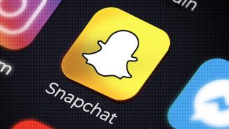 The Snapchat app on a phone screen next to other social media apps