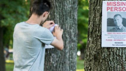 A young man puts up ads for a missing person in the park