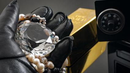 Home invasion and burglary concept with hand in leather gloves holding the loot a diamond and pearl necklace