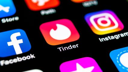 The Tinder logoon a phone screen surrounded by other social apps