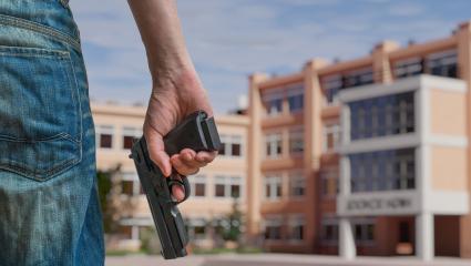 A man holding a gun outside of a high school