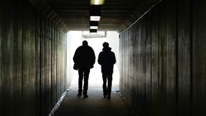 two people walk to the light at the end of a tunnel