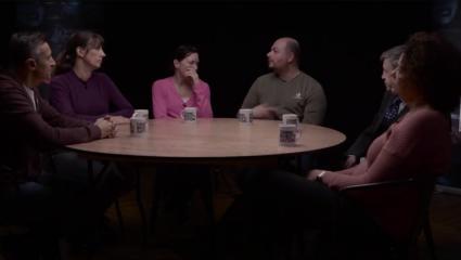 Adults sitting around table talking in a dark room