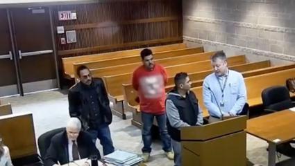 Two men standing in court as one drops a small white bag