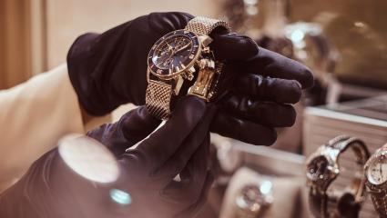 A pair of gloved hands examining expensive jewellery