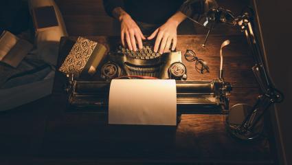 Typing hands of a writer looking for inspiration to start a new novel on his vintage typewriter.