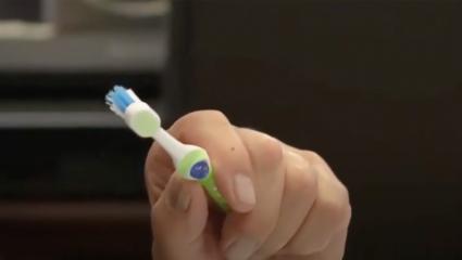 A green and blue toothbrush held in a man's hand