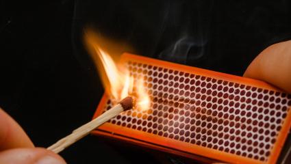 Man's fingers lighting a match