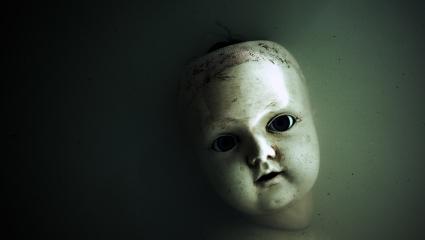 Creepy doll face in dark dirty water