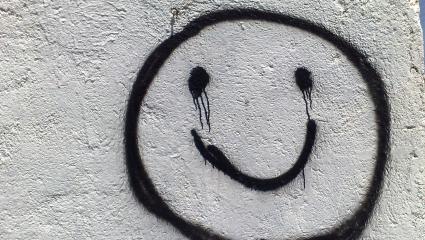 Black graffiti on a white wall of a smiling face