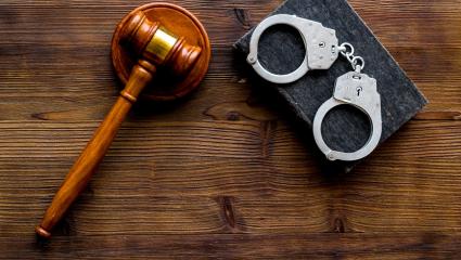 A photograph of a courtroom gavel and police handcuffs