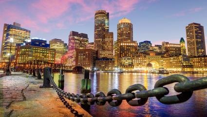 A stock photo showing the Boston Harbour and Financial District at night.
