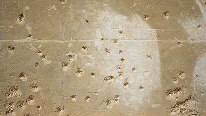 A stock photo showing bullet holes in a concrete wall