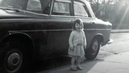 Alissa Moore as a young girl stood in front of a car