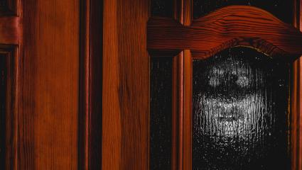 The outline of a face can be seen on the other side of a frosted glass door