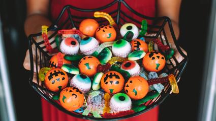 A woman holding a bowl of Halloween sweets