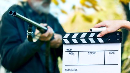 A stock image of a man with a gun and a movie set clapperboard