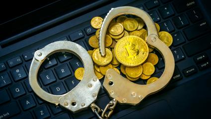 Golden cryptocurrency with handcuffs on computer keyboard