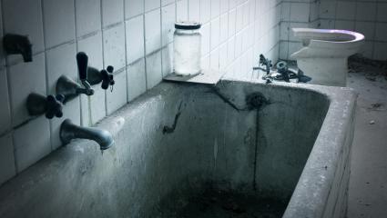 A stock image of a dirty bathtub and broken toilet