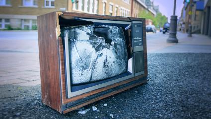 A photograph of a broken TV set discarded at the side of a street