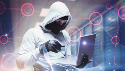 A scammer hold a credit card while using a laptop