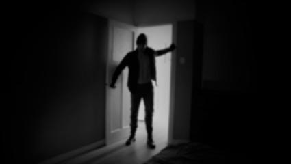 Blurry image of an intruder entering into a dark bedroom
