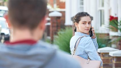 A woman looks over her shoulder as a man is following her