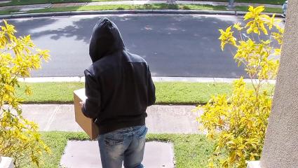 A thief stealing a parcel from a porch