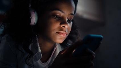 A woman listens to a podcast at night
