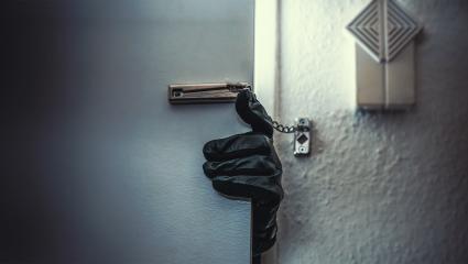 A leather-gloved hand reaching around a door
